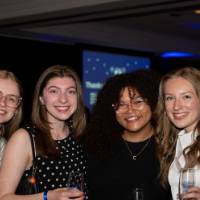 Four grads smile at Toast holding champagne flutes